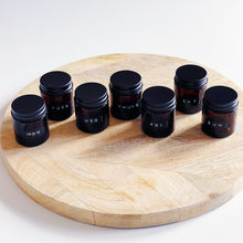 Load image into Gallery viewer, Set Of 7 Mini Amber Glass Jars With Black Lids And Stamped Labels
