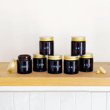 Load image into Gallery viewer, Set Of 7 Mini Amber Glass Jars With Gold Lids And Stamped Labels
