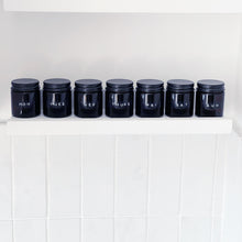 Load image into Gallery viewer, Set Of 7 Mini Amber Glass Jars With Black Lids And Stamped Labels
